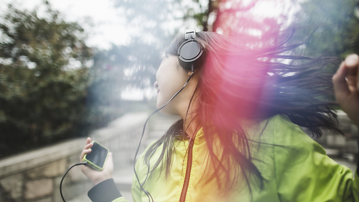 Young woman, outdoors, listening to music and dancing