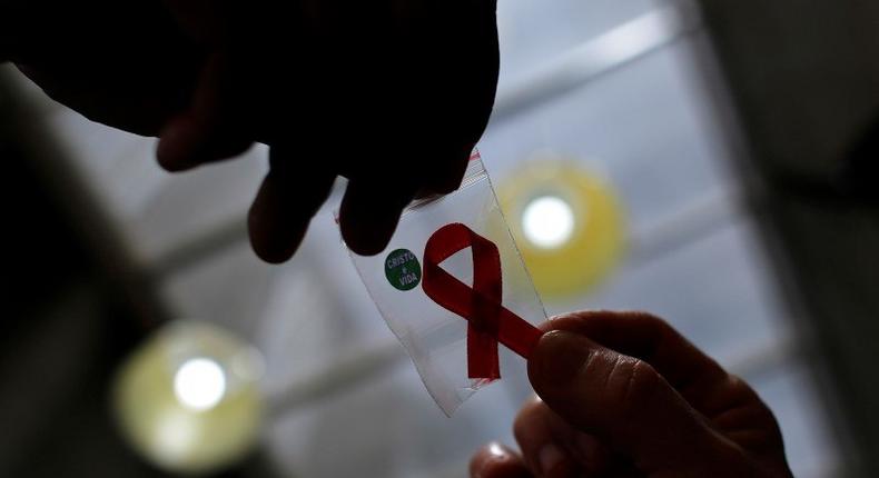 A nurse (L) hands out a red ribbon to a woman, to mark World Aids Day, at the entrance of Emilio Ribas Hospital, in Sao Paulo December 1, 2014. 
