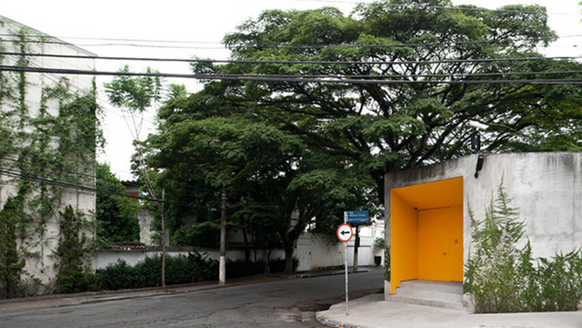 Oto sposób, by nie psuć innym krwi swoim bogactwem: położone na rogu pomarańczowe wejście do pewnego domu w Sao Paulo wydaje się prowadzić do nieciekawego miejsca, z pewnością niewartego uwagi. Tymczasem wiedzie do pięknej, przestronnej, otoczonej basenem willi z długim basenem.