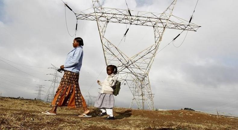 A woman walks her child to school past high voltage electrical pylons on the outskirts of Kenya's capital Nairobi, March 14, 2011.   REUTERS/Thomas Mukoya