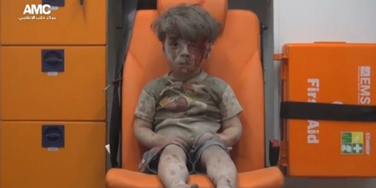 A still image from a video posted on social media shows a boy with bloodied face sitting in an ambulance, after an airstrike