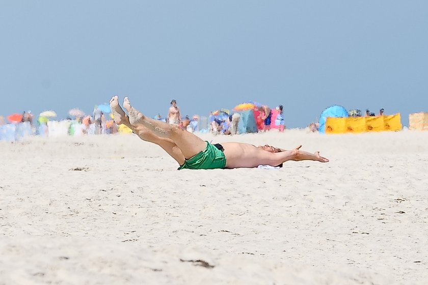 Radosław Sikorski na plaży ćwiczy brzuszki 