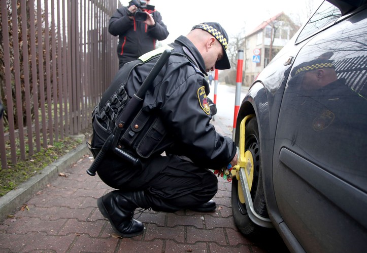 Straż miejska zakłada blokadę na źle zaparkowany samochód na ulicy Turystycznej w Krakowie