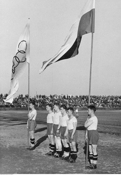 Jucătorii de fotbal depun jurământ în timpul pauzei meciului de fotbal Rush Wilkie Hajduki - Warta Poznan.  Printre steagurile din stânga: Gerard Woodars, Ernest Wilimowski, Edmund Giemsa și Carol Dziwisz