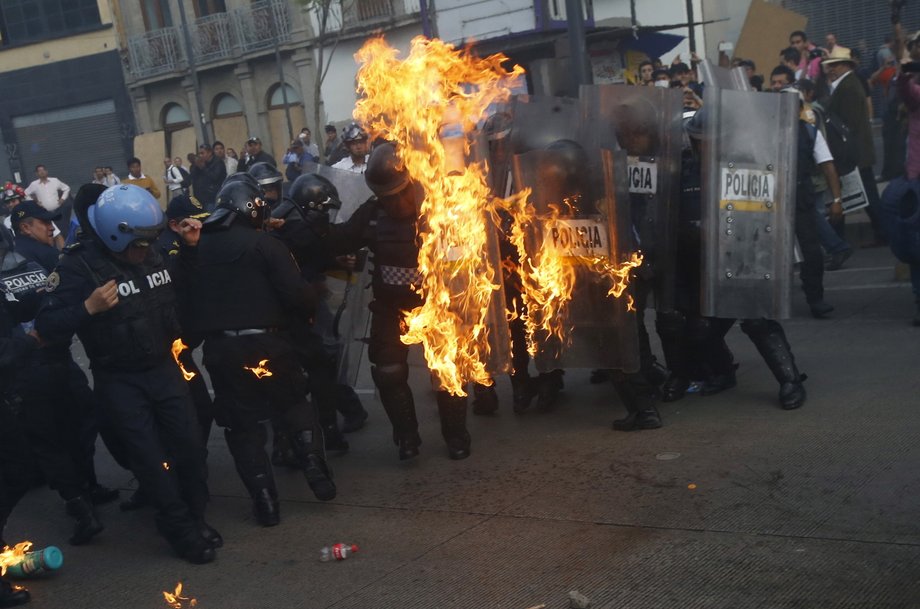 Policemen catch fire after being hit by a Molotov cocktail during a protest to mark the eight-month anniversary of the Ayotzinapa students' disappearance in Mexico City, May 26, 2015.