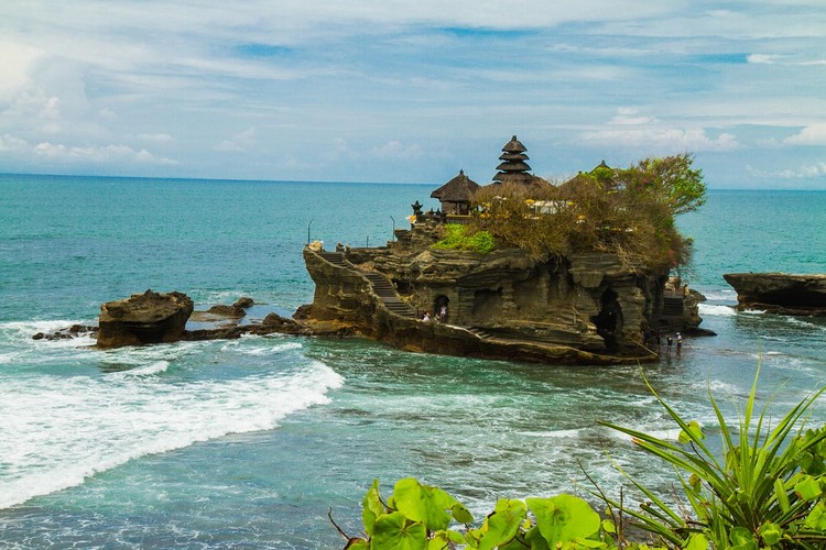 Świątynia Tanah Lot i Las Małp</strong><br /><br /> 

„Ziemia pośrodku morza” jak należało by tłumaczyć nazwę Tanah Lot, to najsłynniejsza pagoda na Bali, znana także jako Świątynia Słońca. Wybudowana została w XVI wieku na skale położonej 50 metrów od brzegu, otoczonej przez Ocean Indyjski po tym, jak to niezwykłe miejsce tak bardzo zachwyciło hinduskiego kapłana Nirartha, że uznał je za święte.<br /><br /> 

Dziś jest to najważniejsza świątynia w pasie siedmiu Pagód, które powstały obok siebie, każda w odległości wzroku. Razem tworzą mur, który ma zabezpieczać wyspę przed złymi mocami, które mogłyby przedostać się od strony oceanu. Podczas odpływu do Tanah Lot można dostać się pieszo. <br /><br />

Zewnętrzna część świątyni jest dostępna dla wszystkich odwiedzających. Do środka mogą jednak wejść wyłącznie Balijczycy. 
Dla wszystkich dostępny jest natomiast Las Małp, który znajduje się niedaleko. Święty Las Małp Padangtegal to jedna z największych atrakcji w całym regionie. Choć turystów przyciąga tu głównie możliwość obserwowania szarych makaków przywykłych do obecności człowieka, warto też wybrać się na spacer pośród bujnej roślinności. Pozostałości świątyni i strzegące jej liczne rzeźby, ukryte pośród bujnej roślinności i wysokich drzew, czynią to miejsce wyjątkowym. <br /><br />