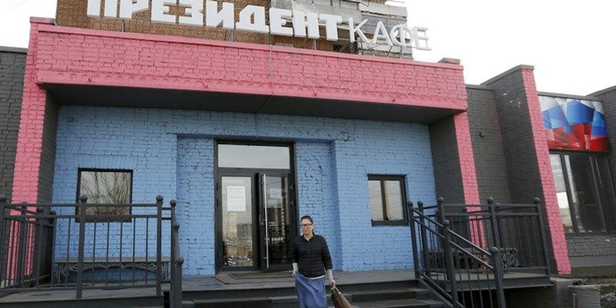 A visitor closes the toilet door as portraits of foreign leaders are seen on a wall at the "President Cafe" in Krasnoyarsk, Siberia, Russia, April 7, 2016.