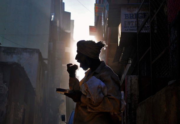 A homeless man eats his breakfast on a street in Bengaluru