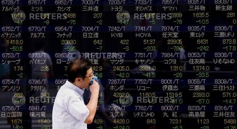 A man walks past a display showing stock prices in Tokyo August 12, 2015. REUTERS/Thomas Peter