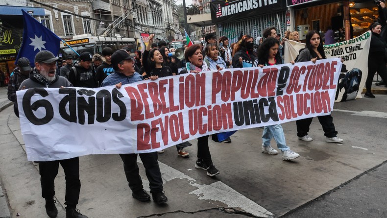 Protesters hold a banner during a march commemorating the sixth anniversary of the social outbreak. Chile marked the sixth anniversary of the 2019 social uprising, known as the Estallido Social or October Revolt, with a commemorative march in Valparaíso. [Photo by Cristobal Basaure Araya/SOPA Images/LightRocket via Getty Images]