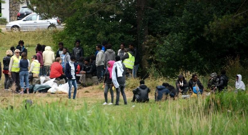 This photo taken on July 03, 2017 shows migrants waiting in a field near the port of Calais, northern France