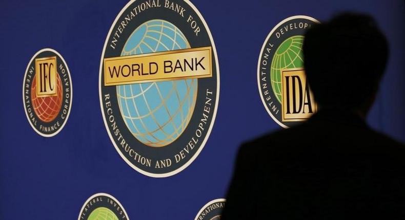 A man is silhouetted against the logo of the World Bank at the main venue for the International Monetary Fund (IMF) and World Bank annual meeting in Tokyo October 10, 2012. 