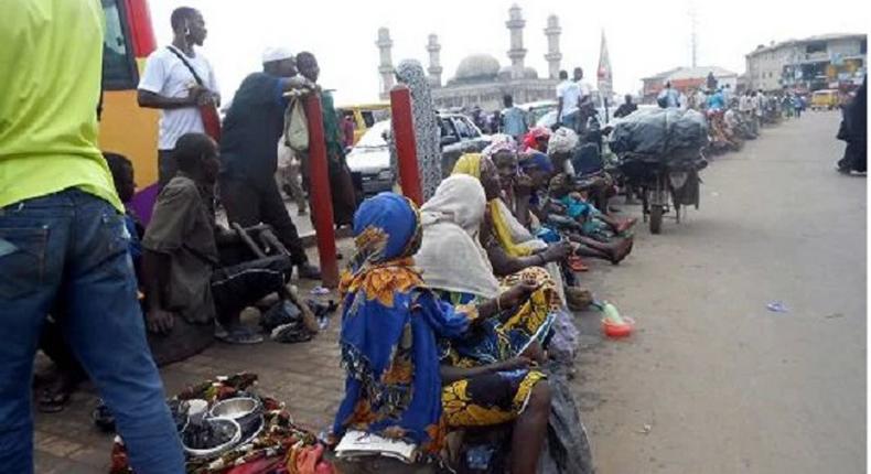 A group of roadside beggars gather at a location hoping to receive alms.