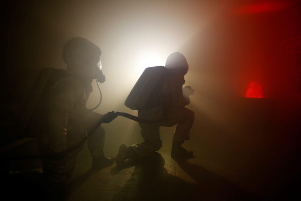 Students wears firefighting gears as they simulate a fire onboard a vessel at the French Navy school