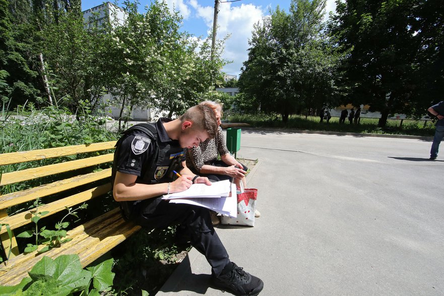 Ukraiński policjant rozmawia z kobietą na miejscu ataku rakietowego w Charkowie