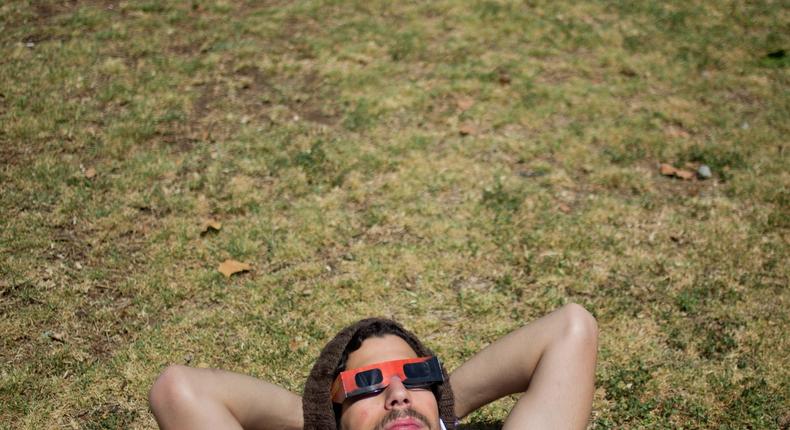 A man looks up at the sun wearing protective glasses to watch a partial solar eclipse in the town of Givatayim, near Tel Aviv, Israel.