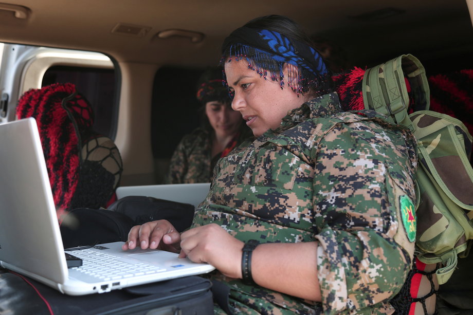 A Kurdish fighter from the People's Protection Units (YPG), operating alongside the Syrian Democratic Forces (SDF), sits inside a vehicle as she works on a laptop in the town of Hisha after the SDF took control of the area from ISIS, in the northern Raqqa countryside, Syria, November 14, 2016.