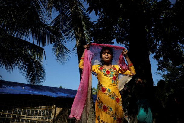 Taslima, a 13-year-old Rohingya refugee adjusts her scarf as she stands next to her temporary settle