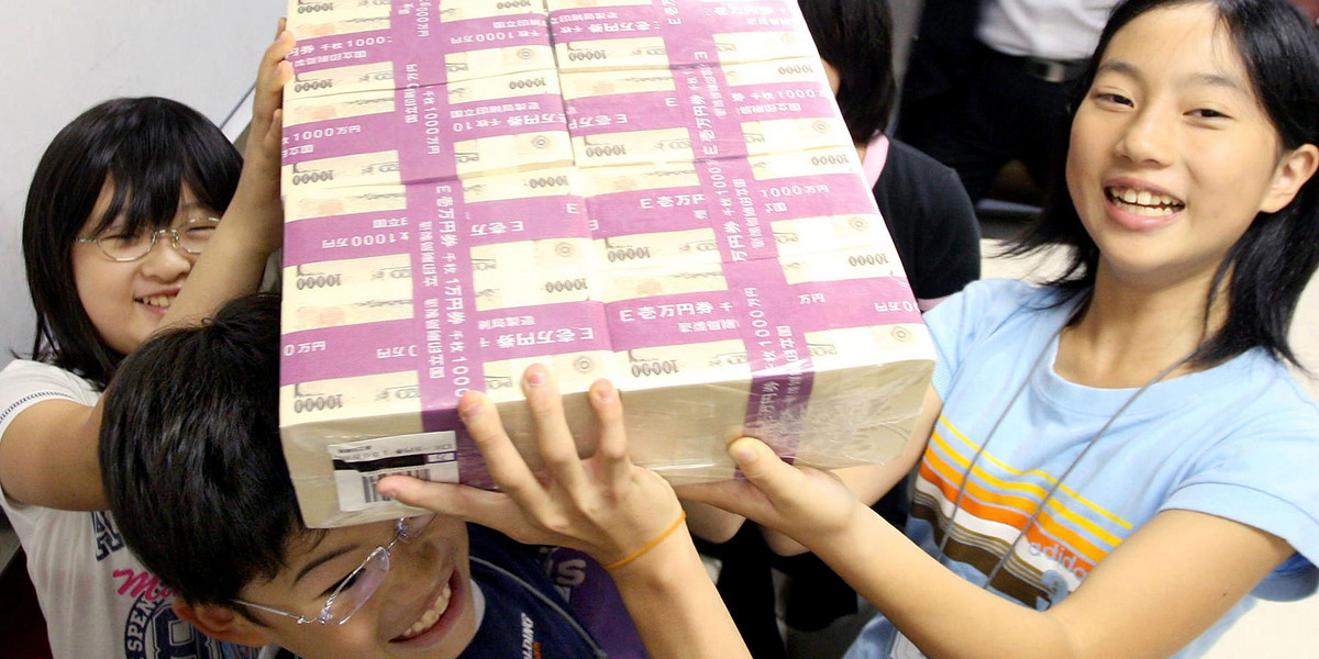 Tokyo. Dzieci jednej z japońskich szkół trzymają banknowy warte 100 milionów jenów