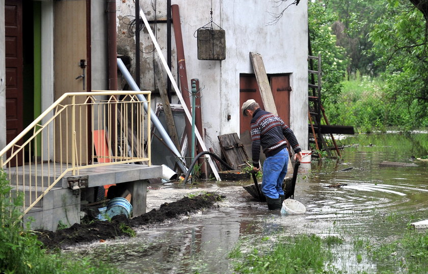 Mężczyzna z taczką na zalanym przez powódź podwórku