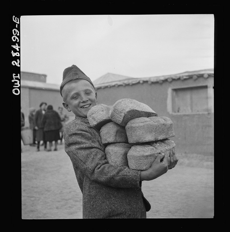 Chłopiec niosący bochenki chleba z mąki zapewnionej przez Czerwony Krzyż (domena publiczna)
