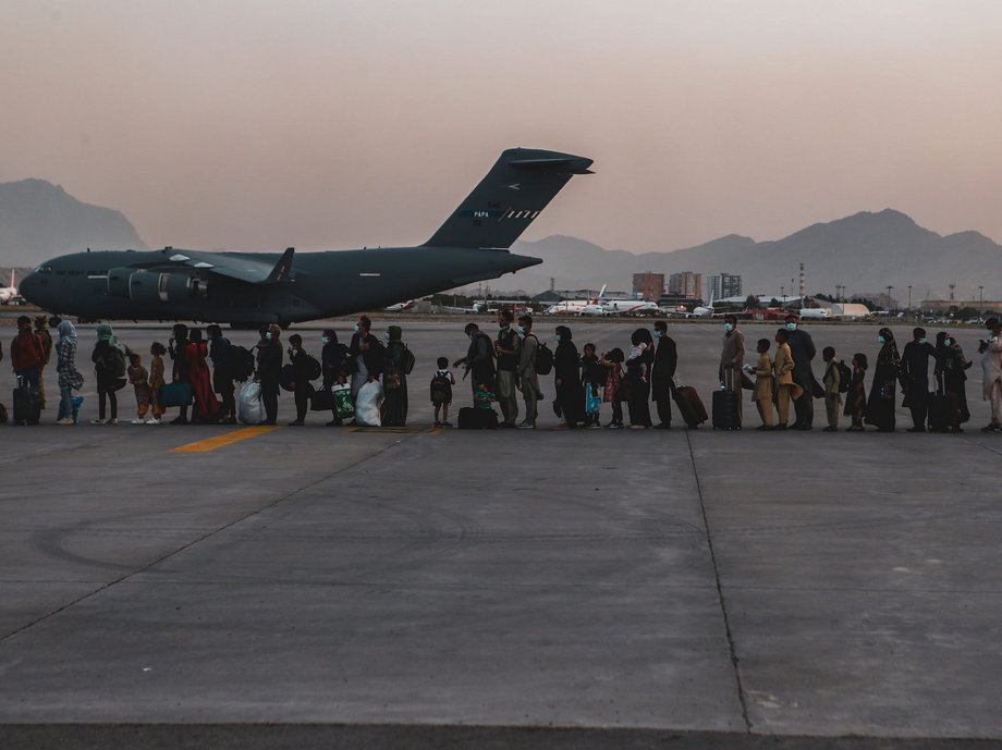Ewakuowani czekają na wejście na pokład C-17 na międzynarodowym lotnisku Hamid Karzai w Kabulu 23 sierpnia 2021 r. 