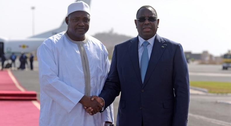 Senegal's President Macky Sall (R) shakes hands with the new President of Gambia Adama Barrow prior to leaving the Senegalese capital Dakar on January 26, 2017