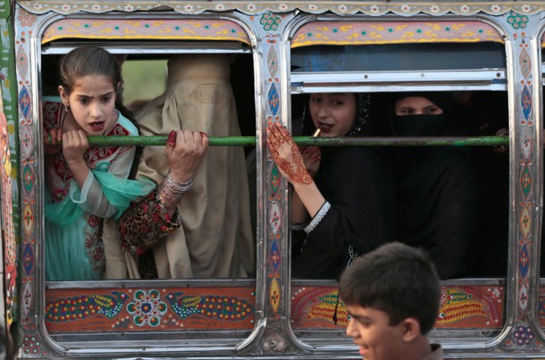 Women riding in a van react to something happening outside the van in Rawalpindi