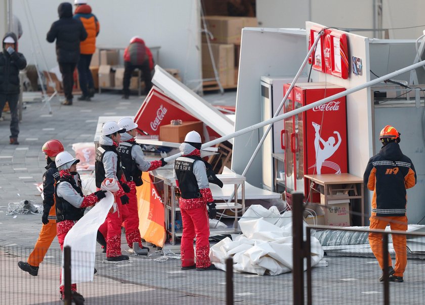 Firefighters assess the damage to a food stall that was blown over by the wind