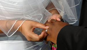 A bride inserting a ring on her grooms finger