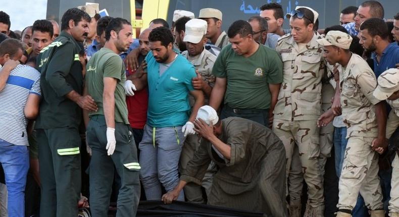 Policemen and medics gather around the body of a migrant along the shore in the Egyptian port city of Rosetta on September 22, 2016, during a search operation after a boat capsized in the Mediterranean