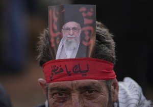 Pristalica Hezbolaha sa trakom oko glave na kojoj na arapskom piše: „Na usluzi, o Hamnei“ i drži portret iranskog vrhovnog vođe ajatolaha Alija Hamneija tokom skupa ispred iranske ambasade u Bejrutu, Liban.