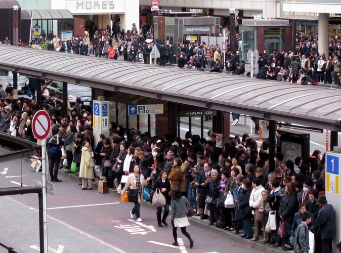 Dziesiątki pasażerów oczekujących na autobus przed dworcem kolejowym w Jokohamie