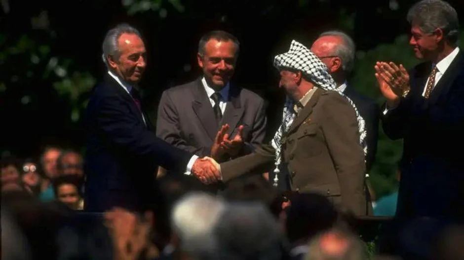 Lider PLO Jaser Arafat (desno) rukuje se sa izraelskim ministrom spoljnih poslova Šimonom Peresom na potpisivanju Sporazuma iz Osla dok američki predsednik Bil Klinton (krajnje desno) aplaudira | Foto: Getty Images