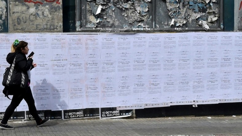 A woman walking past posters with the names of 19 women murdered by October 2018: Uruguay saw a record number of murders in 2018