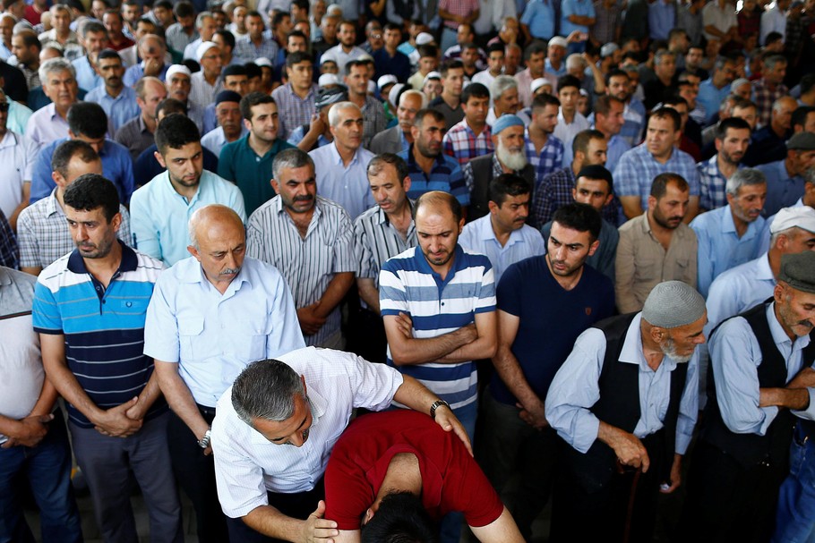 A family member of a victim of a suicide bombing at a wedding celebration mourn over a coffin during a funeral ceremony in the southern Turkish city of Gaziantep