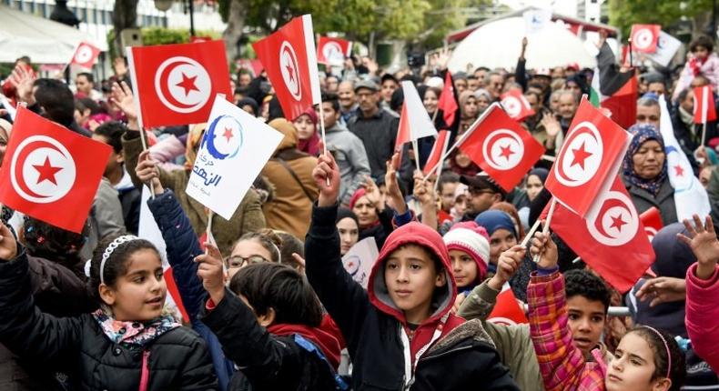 Tunisians wave their national and party flags of the Islamist Ennahdha Party during a rally on January 14, 2017 in the Habib Bourguiba Avenue in the capital Tunis to mark the sixth anniversary of the 2011 revolution