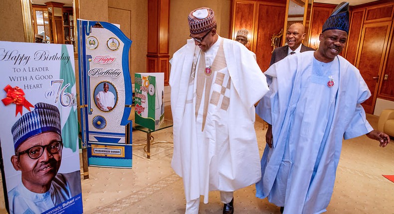 President Muhammadu Buhari looking at birthday gifts presented to him while walking alongside Ibikunle Amosun.