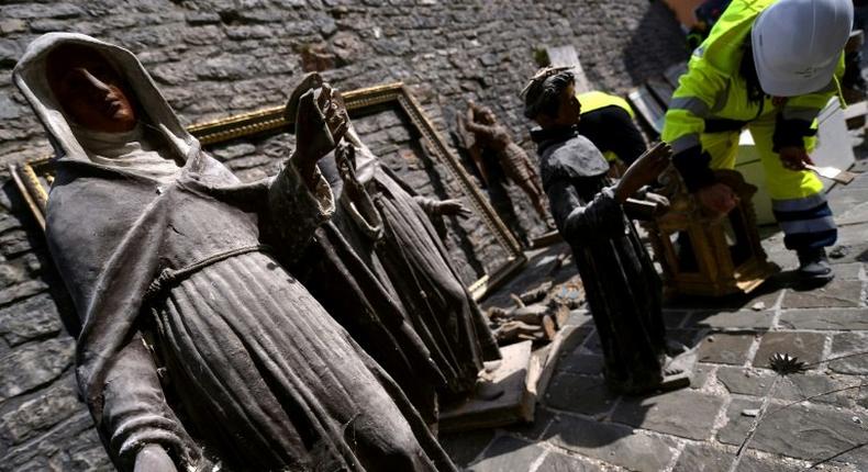 A volunteer on the blue helmet brigade to rescue historic artwork cleans statues recovered from the San Francesco di Visso