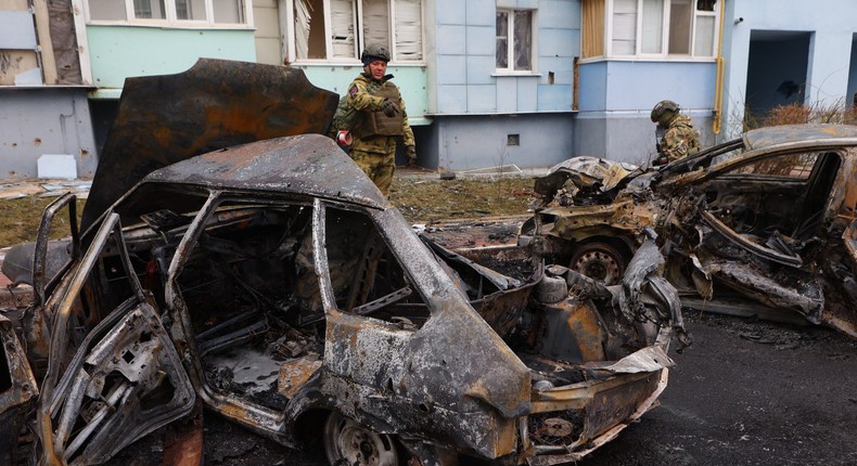 Russian soldiers standing by burned-out cars in Belgorod following aerial attacks on March 22, 2024.STRINGER/AFP via Getty Images