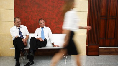 Two businessmen looking at woman's legs