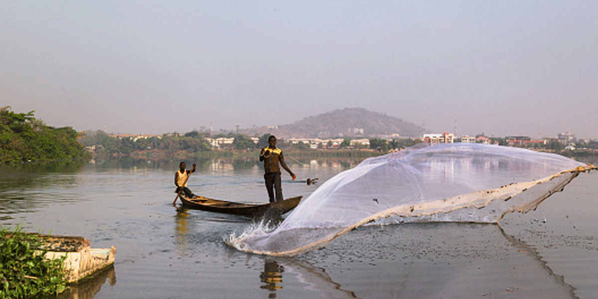 A fisherman casting net from his boat. Jabi Lake in Abuja FCT, Nigeria.
