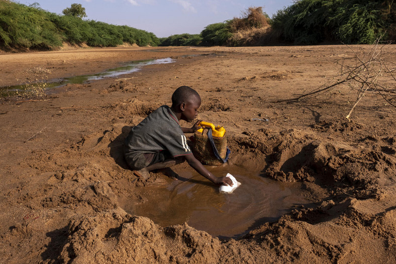 Dziecko nabiera wodę z wyschniętej rzeki w Somalii