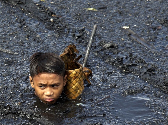 Filipiński chłopiec zbiera odpadki po pożarze dzielnicy slumsów w Navotas na przedmieściu Manili