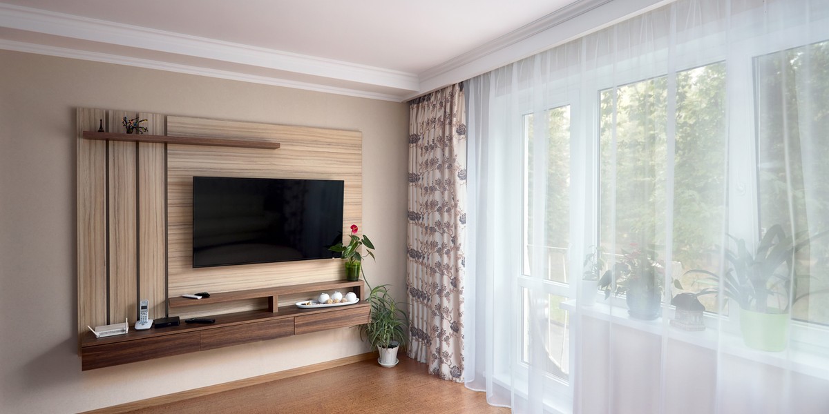 Modern apartment living room with large TV over wooden cabinet cork floorboards and glass door to ba