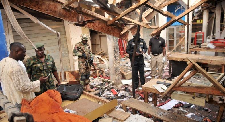 Soldiers and policemen are pictured at the scene where two female suicide bombers blew themselves up at a mobile phone market in the northern Nigerian city of Kano November 18, 2015. The explosions occurred at the Farm Centre phone market, near the center of Nigeria's second biggest city, killing at least 12 people and wounding around 60 others, a Red Cross official and police said. REUTERS/Stringer
