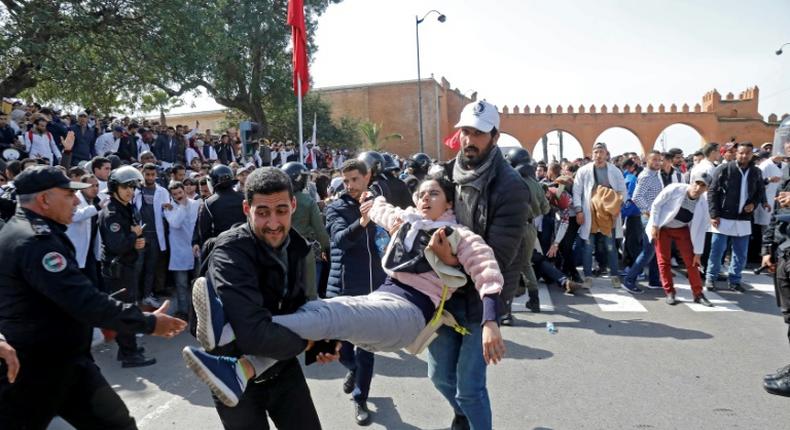 Moroccan public school teachers help a colleague who was injured in a scuffle with police during a demonstration in the capital Rabat on February 20, 2019