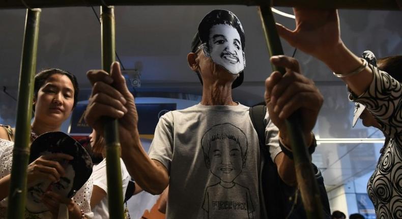 Activists standing behind makeshift bars wearing masks of Thai human rights activist Jatupat “Pai Boonpattararaksa, who was arrested in early December 2016