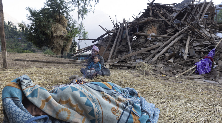 Egy fiú alszik az összedőlt házuk elött