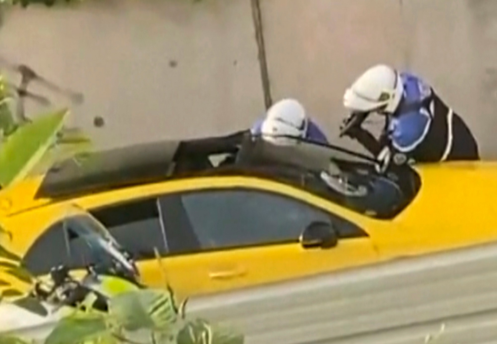 Na snímke z videa dvaja policajti sa pýtajú mladého vodiča, jeden z nich mieri zbraňou na okno žltého auta, ktorého zastavili počas dopravnej kontroly.